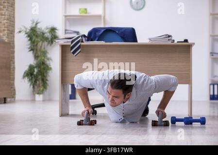 Handsome male employee doing exercises in office Stock Photo