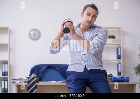 Handsome male employee doing exercises in office Stock Photo