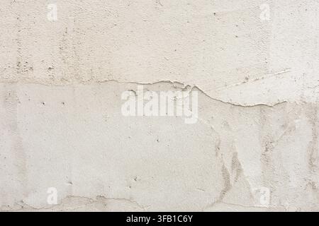 Rough plaster wall background, close-up of light beige concrete texture with uneven layers and scratches. Stock Photo