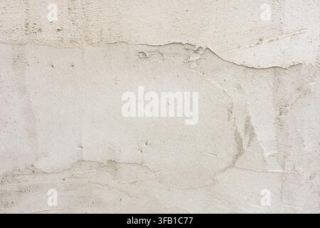 Rough plaster wall background, close-up of light beige concrete texture with uneven layers and scratches. Stock Photo