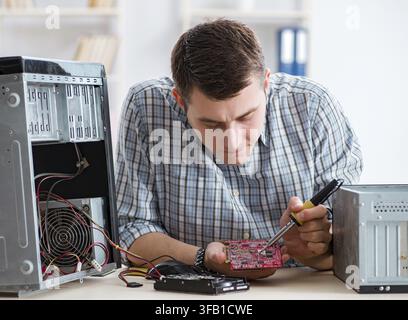 The young technician repairs computers in the workshop Stock Photo