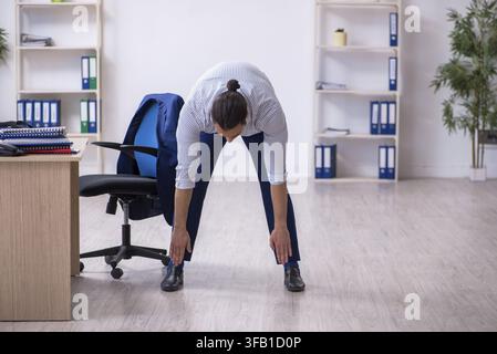 Handsome male employee doing exercises in office Stock Photo