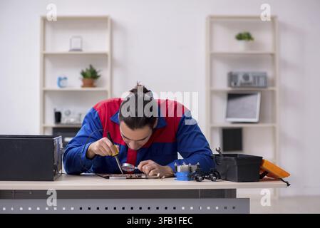 Young male mechanic repairs computer PC Stock Photo
