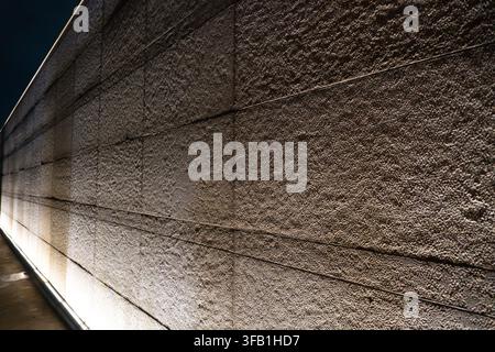 Textured concrete wall illuminated at night. Stock Photo