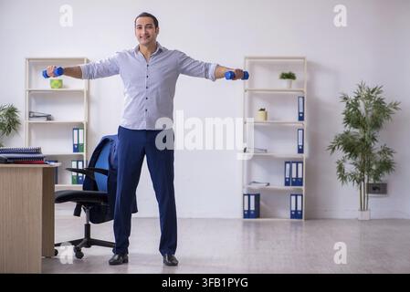 Handsome male employee doing exercises in office Stock Photo