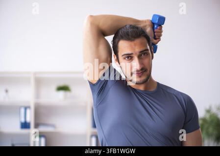 Young male employee doing sports exercises in office Stock Photo