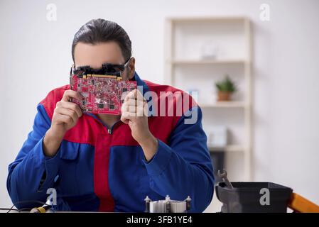 Young male mechanic repairs computer PC Stock Photo