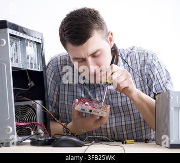 The young technician repairs computers in the workshop Stock Photo