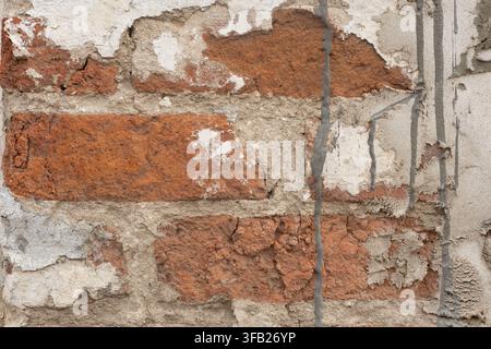 Old red brick wall texture, damaged plaster on brickwork with concrete cement drips, grunge weathered architectural background. Stock Photo