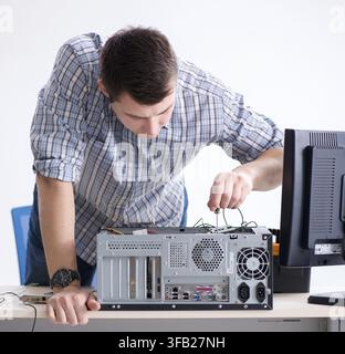 The young technician repairs computers in the workshop Stock Photo