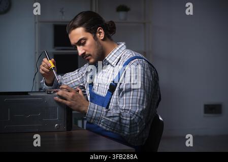 Young technician repairs computers in the workshop at night Stock Photo