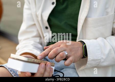 Man checks navigation route on smartphone while charging device from portable power bank during hike. Concept of technology and travel integration for Stock Photo