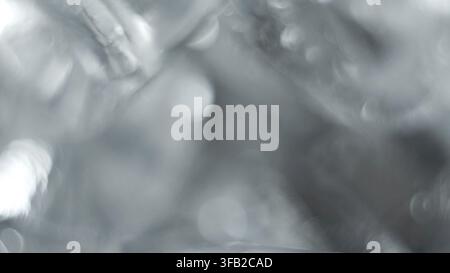 Abstract silver reflective texture background displaying glowing blurred light and shiny bokeh circles Stock Photo