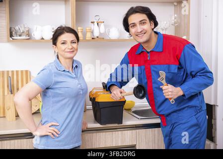 The young male mechanic repairs the faucet Stock Photo