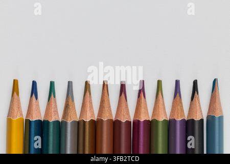 Macro close up of colorful metallic pencils lined up in a horizontal row on white background with copy space Stock Photo