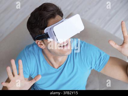 Young man wearing VR glasses relaxing on the couch sofa Stock Photo