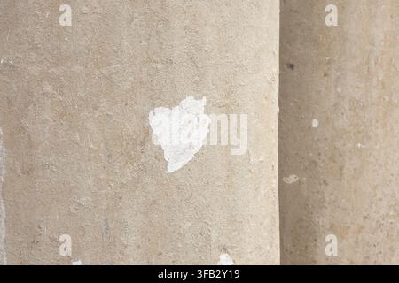 Beige concrete column texture, close-up of curved cement surface with white paint smear, rough architectural detail background. Stock Photo