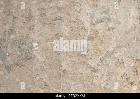 Rough concrete wall texture, close-up of weathered beige cement surface with rugged stone structure, grunge architectural background. Stock Photo