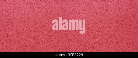 Red rough plaster wall showing textured granular surface for backgrounds Stock Photo