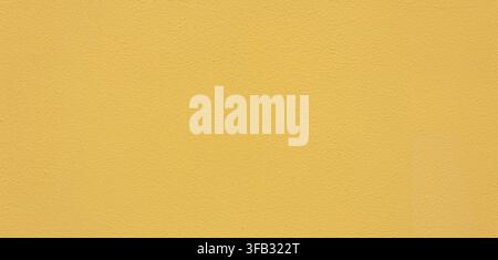 Yellow wall surface featuring a grainy painted texture for background use Stock Photo