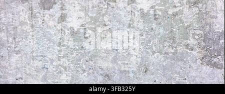 Grungy textured surface showing worn plaster and faded posters, creating an abstract background Stock Photo