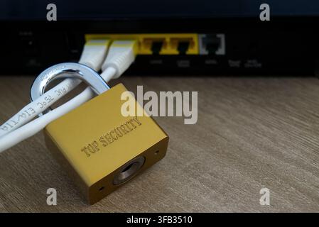 Detailed macro shot focusing on a gold padlock securing network cables plugged into a router. Concept of IT security, data confidentiality, and system Stock Photo