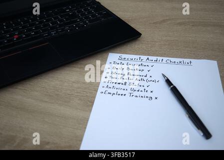 Angled top view of an office workspace showing a security audit checklist with checkboxes and a laptop. A professional setting for IT security, GDPR, Stock Photo