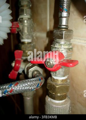 In a modern setting a brass ball valve with a vibrant red butterfly handle connects snugly to a metal plastic pipe showcasing precision design and fun Stock Photo