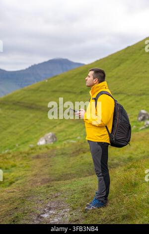Man flying drone during hike on Kalsoy Island Stock Photo