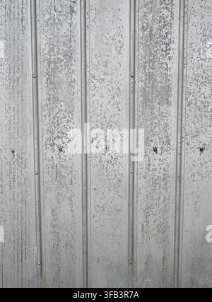 Vertical close-up view of weathered corrugated tin metal with a silver galvanized surface Stock Photo