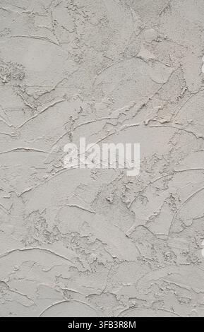 Vertical view of sand colored skip trowel stucco wall surface with rough, uneven texture, arc shaped marks, coarse gritty finish, and varied stucco Stock Photo