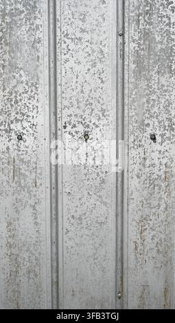 Vertical close-up view of weathered corrugated tin metal wall surface with a silver galvanized finish Stock Photo