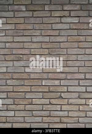 Vertical view of varicolored brown brick and mortar wall surface with porous, uneven bricks and smooth faces Stock Photo