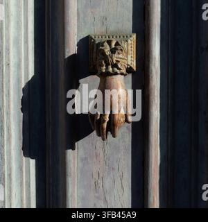 Old metal hand knocker on a grey wooden door Stock Photo