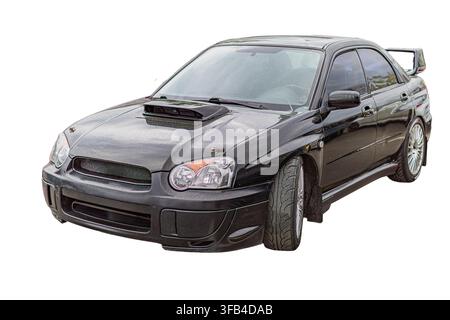 Dark sedan on white background, showcasing sleek design, sporty wheels, black hood scoop, glossy finish, angular headlights, silver rims, smooth aerod Stock Photo