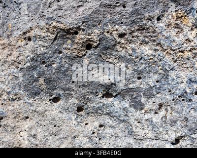 surface of black armenian tuff stones in ancient defensive fortification wall of Hovhannavank Monastery in Armenia lit by sun light Stock Photo