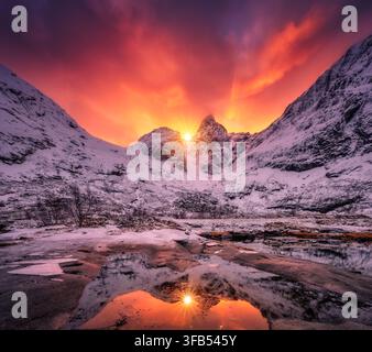 Dramatic red sunset sky over snow covered mountains in Lofoten Stock Photo