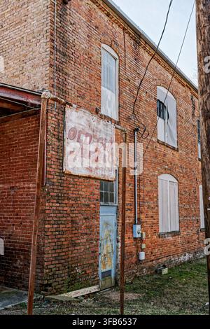 Old vintage red brick two story building with a sign for Old Gin Village that has been abandoned in Wetumpka Alabama, USA. Stock Photo