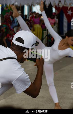 Man photographs a dancer performing in a white leotard at El Carnavalito in Ciego de Ávila, Cuba, on August 21, 2026. Stock Photo