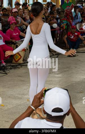Man photographs a dancer performing in a white leotard at El Carnavalito in Ciego de Ávila, Cuba, on August 21, 2026. Stock Photo