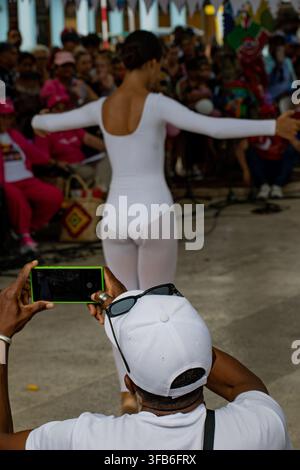 Man photographs a dancer performing in a white leotard at El Carnavalito in Ciego de Ávila, Cuba, on August 21, 2026. Stock Photo