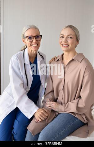 Female doctor and patient, smiling at camera in medical office Stock Photo