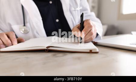 Closeup crop view doctor taking clinical notes in notebook Stock Photo