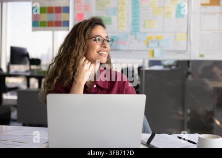 Smiling businesswoman planning strategy, thinking on creative ideas at desk Stock Photo