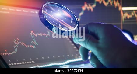 Financial analyst using a magnifying glass to examine stock market data on a digital screen. Stock Photo