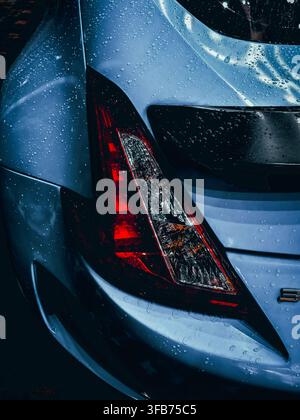 Close up of sports car rear taillight with water droplets in dramatic lighting Stock Photo