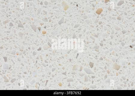 Close up of a polished white terrazzo surface with small speckled pebbles and beige stone chips, a seamless background texture for interior design Stock Photo