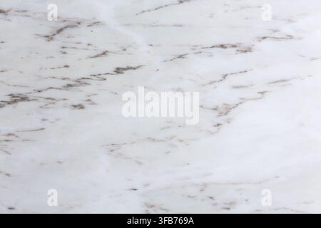 Close up of a natural white marble surface showing fine brown and grey veining across a smooth polished stone slab. Stock Photo