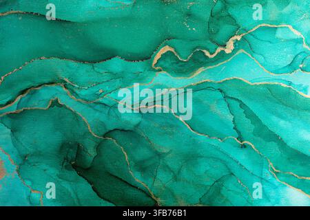 Hand painted fluid art in turquoise and emerald tones with metallic gold lines forming a marbled, wave like texture across the canvas. Stock Photo