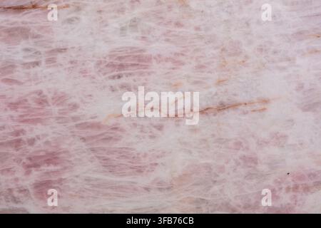 Close up of a polished pink quartzite slab showing soft rose crystal patterns and thin rust coloured veins, a natural stone texture background for Stock Photo